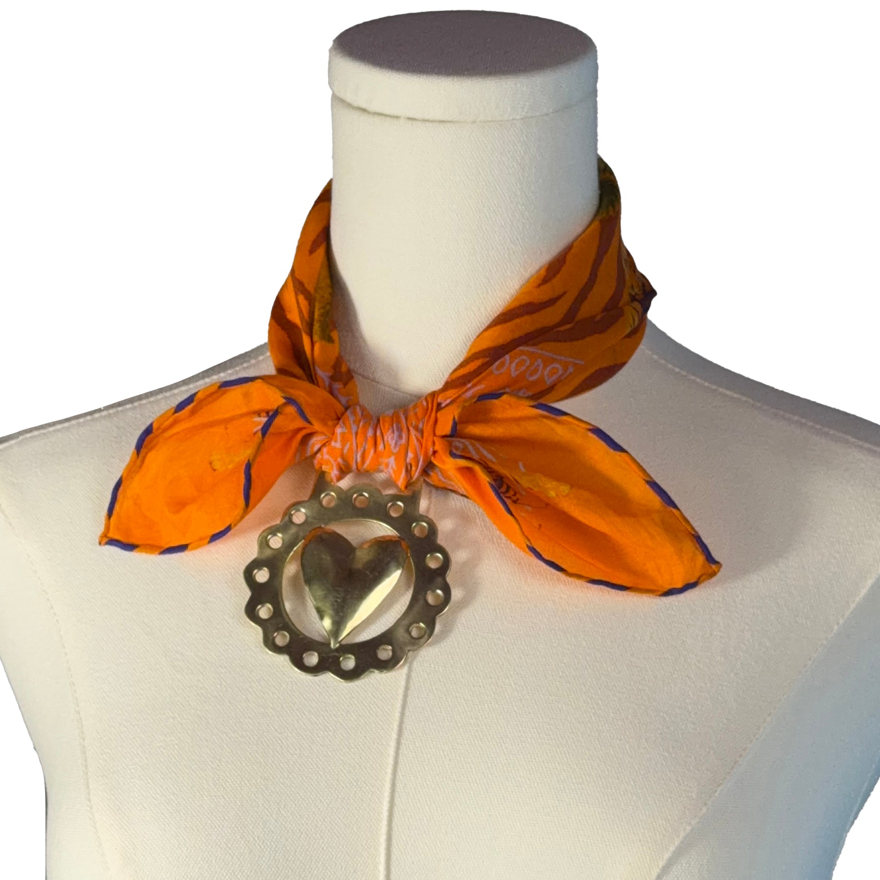 Orange scarf with a heart-shaped brooch on a mannequin
